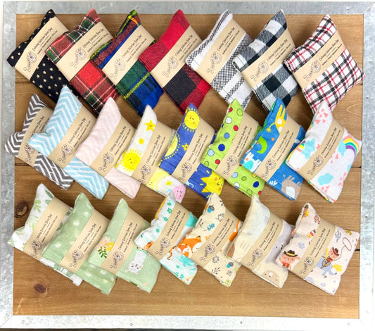 Collection of colorful fabric cat kickers pouches with various patterns on a wooden surface.|Collection de pochettes colorées en tissu pour chats, avec différents motifs, posées sur une surface en bois.