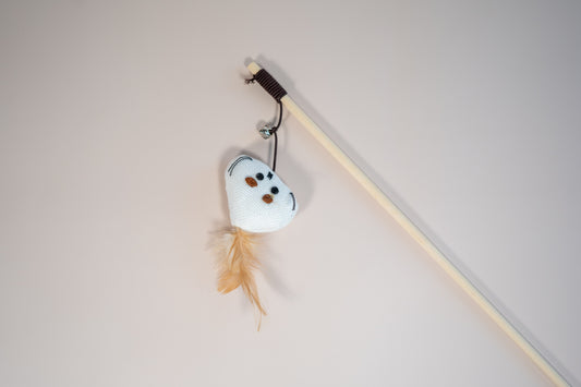 Close view of a cat teaser in head mouse shaped with a feather on the head. | Vue rapprochée de l'agace-chat en forme de tête de souris avec plume sur la tête.