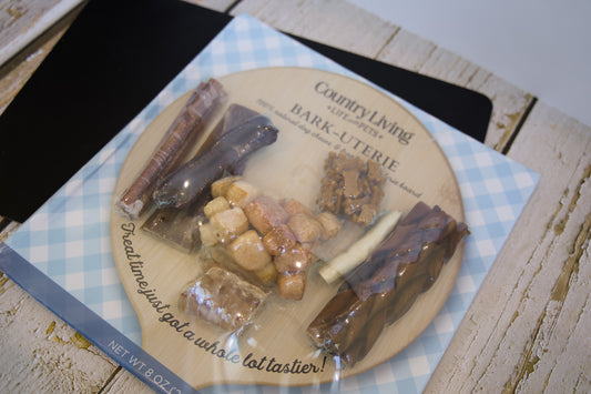 Dog treats on a 'Country Living' branded plate with a checkered napkin underneath.|Des friandises pour chiens sur une assiette de la marque « Country Living », avec une serviette à carreaux en dessous.