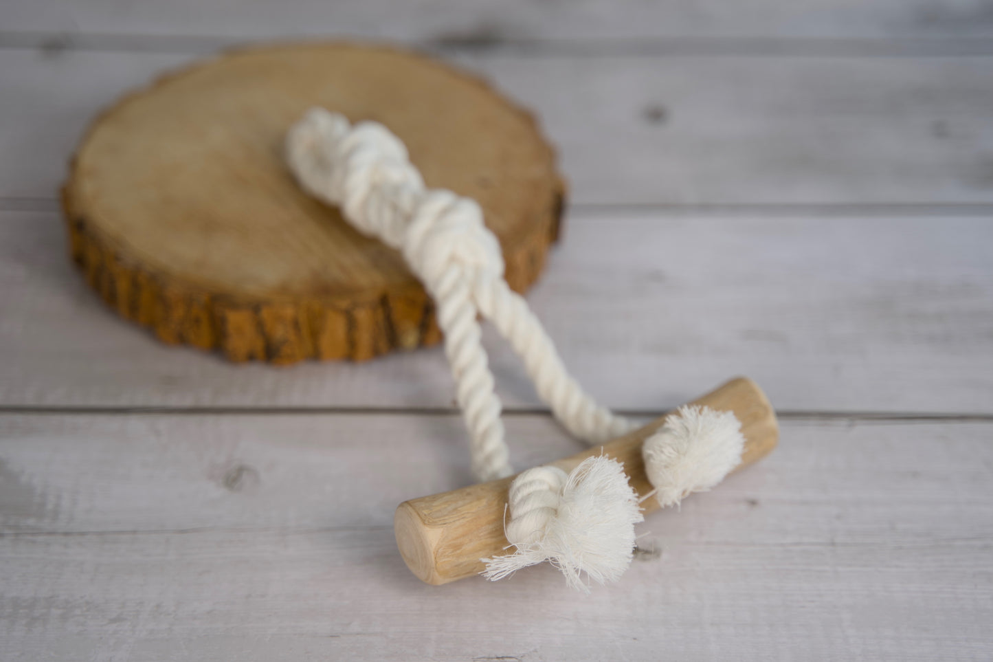 Jouet pour chien avec corde et pièce en bois, posé sur une surface en bois.
