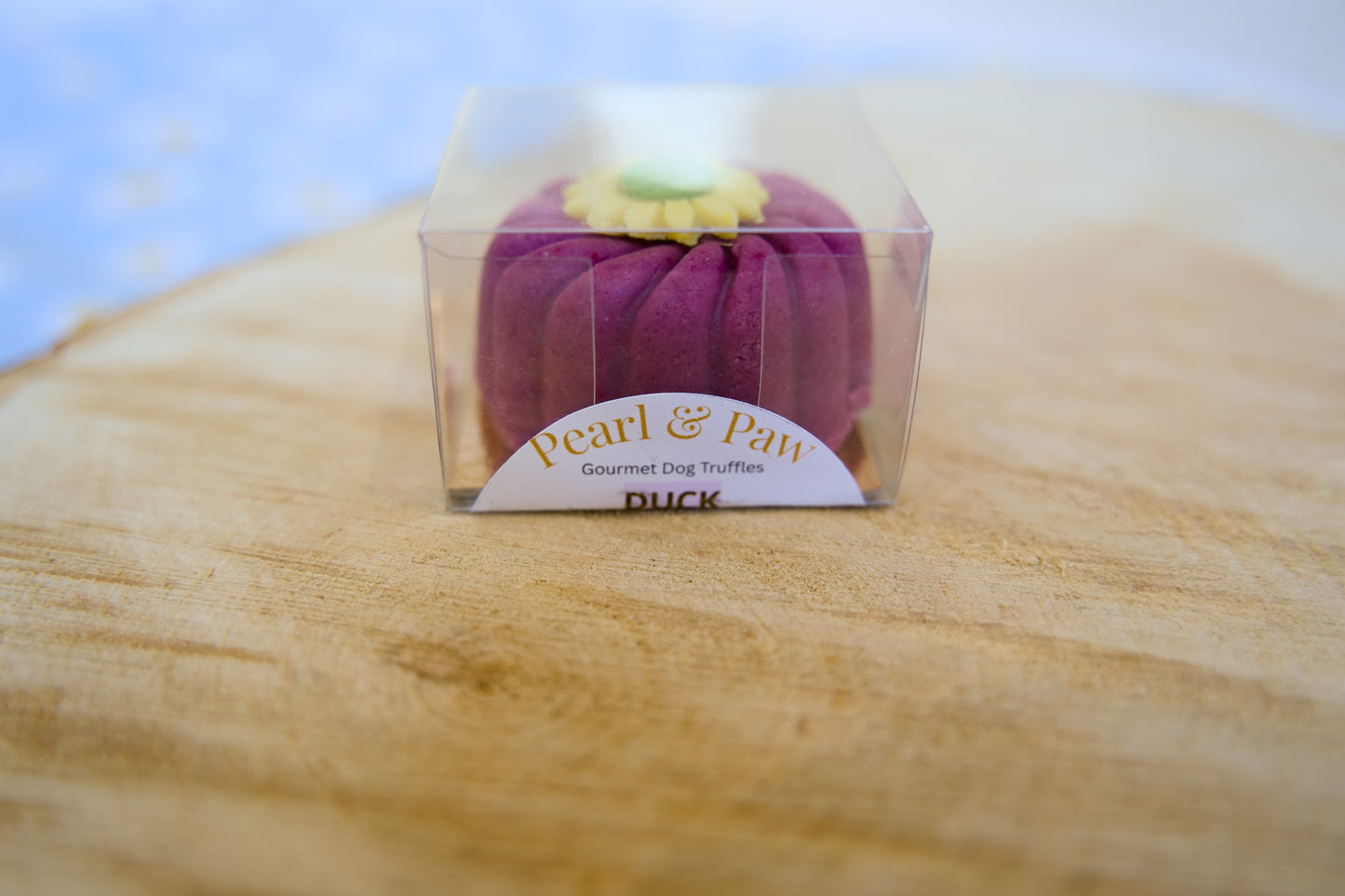 Purple dog truffle in a clear packaging box on a wooden surface with a blue gradient background.