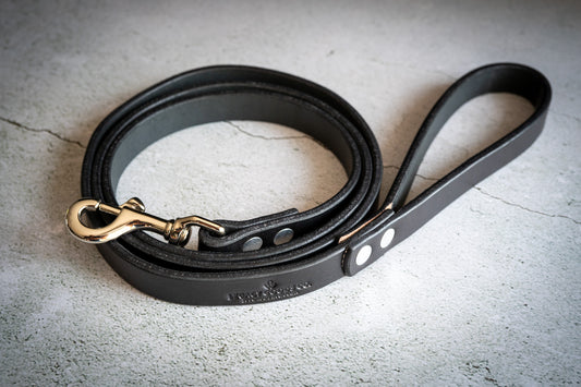 Handmade leather dog leash wrapped around itself. | Laisse pour chien en cuir artisanale enroulée autour d'elle-même.
