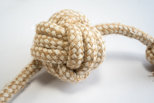Close-up view of the monkey fist ball for dogs made from cotton rope and sisal with knots at the ends. | Vue rapprochée de la balle de poing de singe pour chiens en corde de coton et sisal avec noeuds aux extrémités.