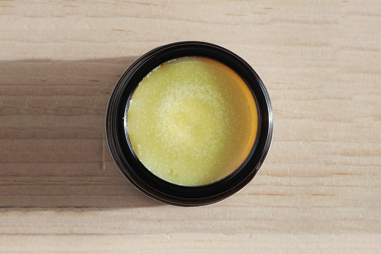 Dog nose balm in a black container on a wooden surface.