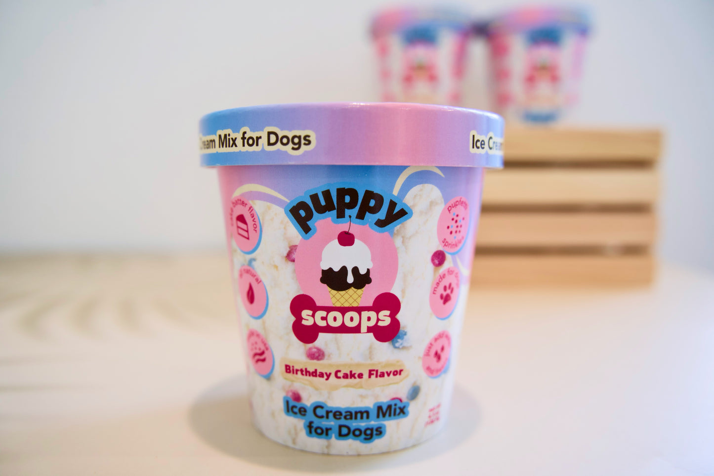Birthday cake flavour Ice cream mix for dogs with colorful packaging on a wooden surface.