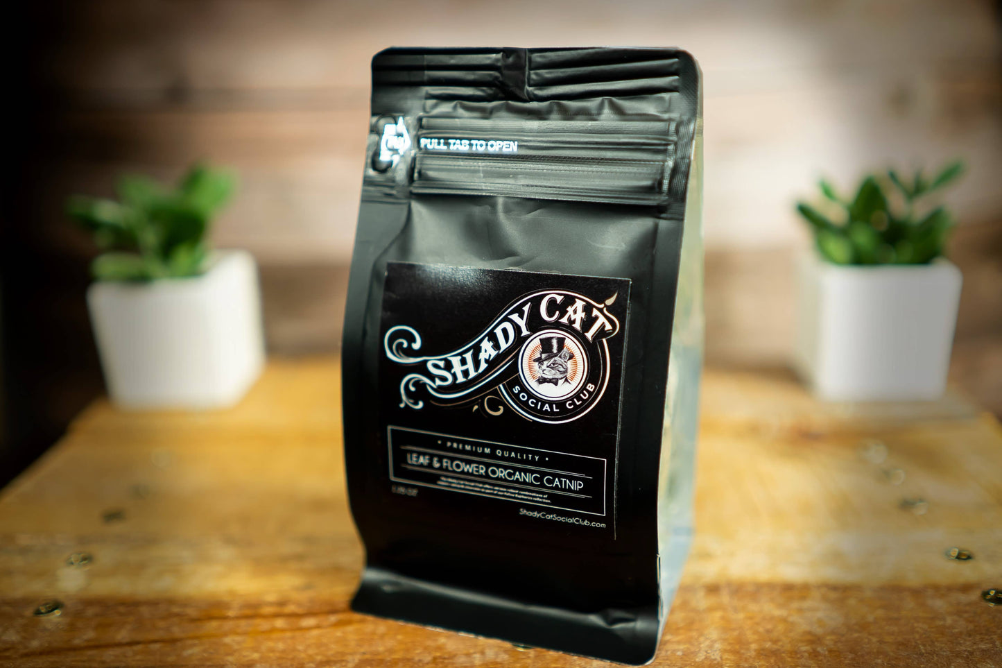 Un sachet souple noir de « Shady Cat Special Mix 'Leaf & Flower Organic Catnip' » posé sur une table en bois.