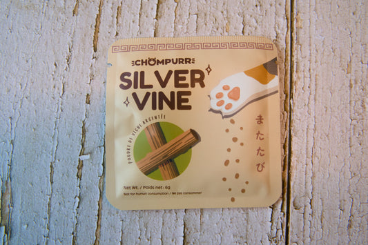 A single packet of Silver Vine cat treats placed on a white wooden surface.|Un sachet de friandises pour chats à la vigne d'argent posé sur une surface en bois blanc.