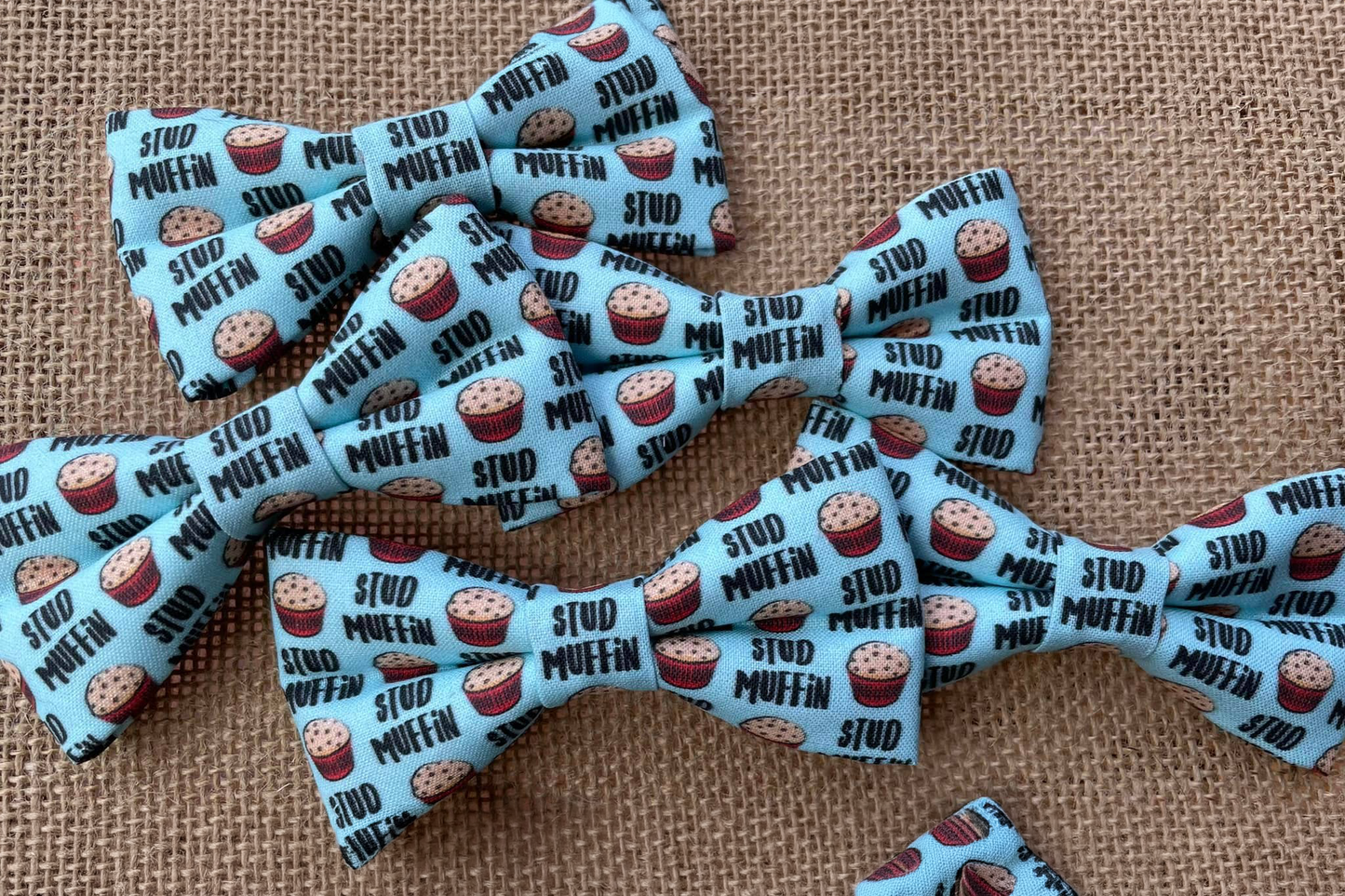 Multiple dog and cats bow ties with stud muffin pattern on a textured fabric background.