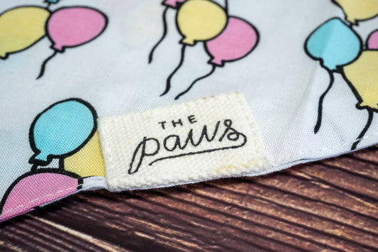Close-up of The Paws logo on dog birthday bandana. | Gros plan sur le logo The Paws sur le bandana d'anniversaire pour chien.