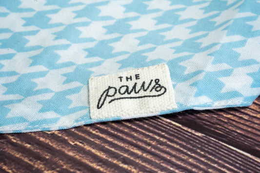 Close-up of The Paws logo on dog bandana with steele patterns. | Gros plan sur le logo The Paws sur bandana pour chien avec motifs de pied-de-poule.