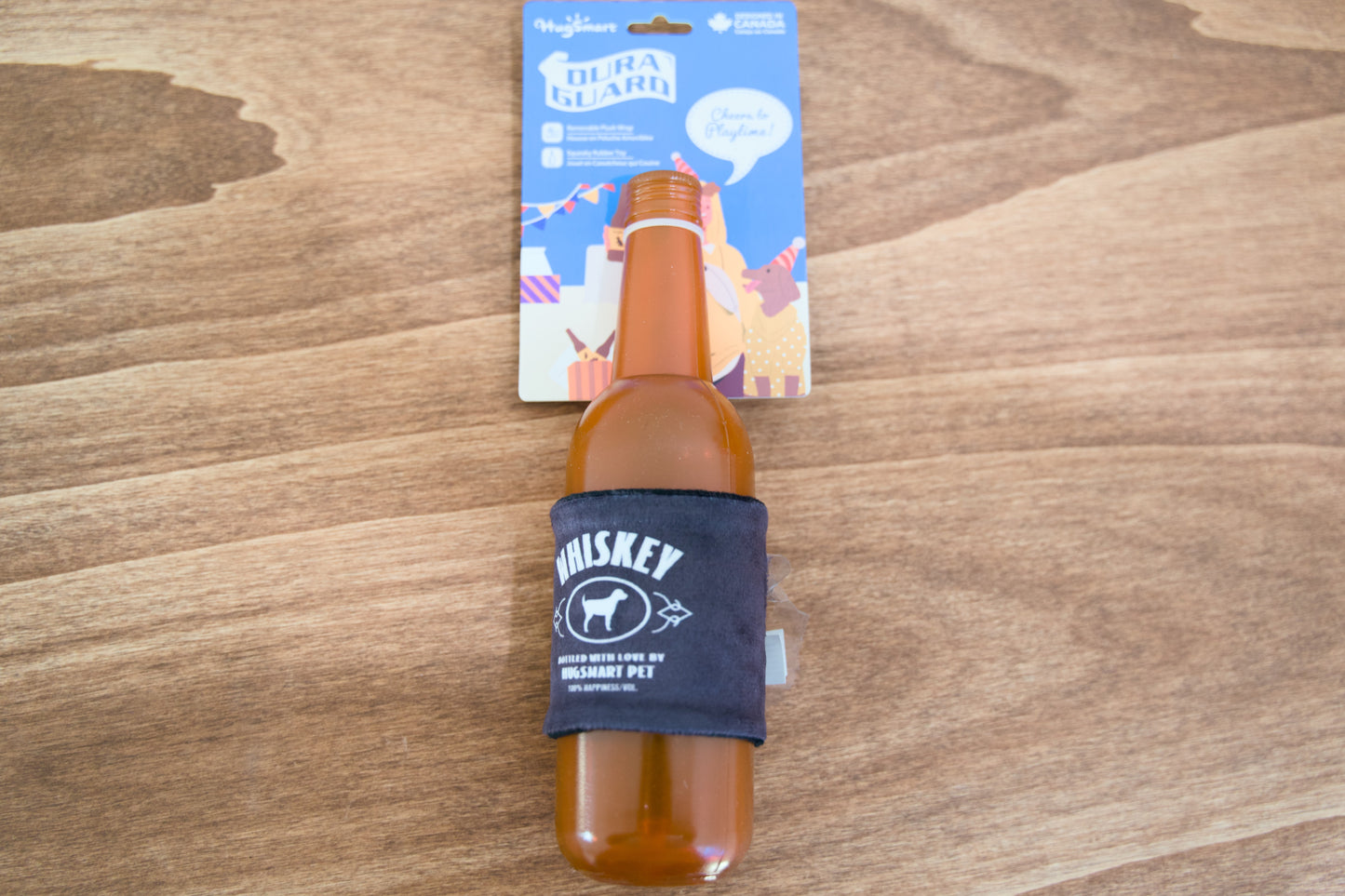 Bottle of whiskey for dogs with a blue sleeve on a wooden surface, with a product packaging in the background.