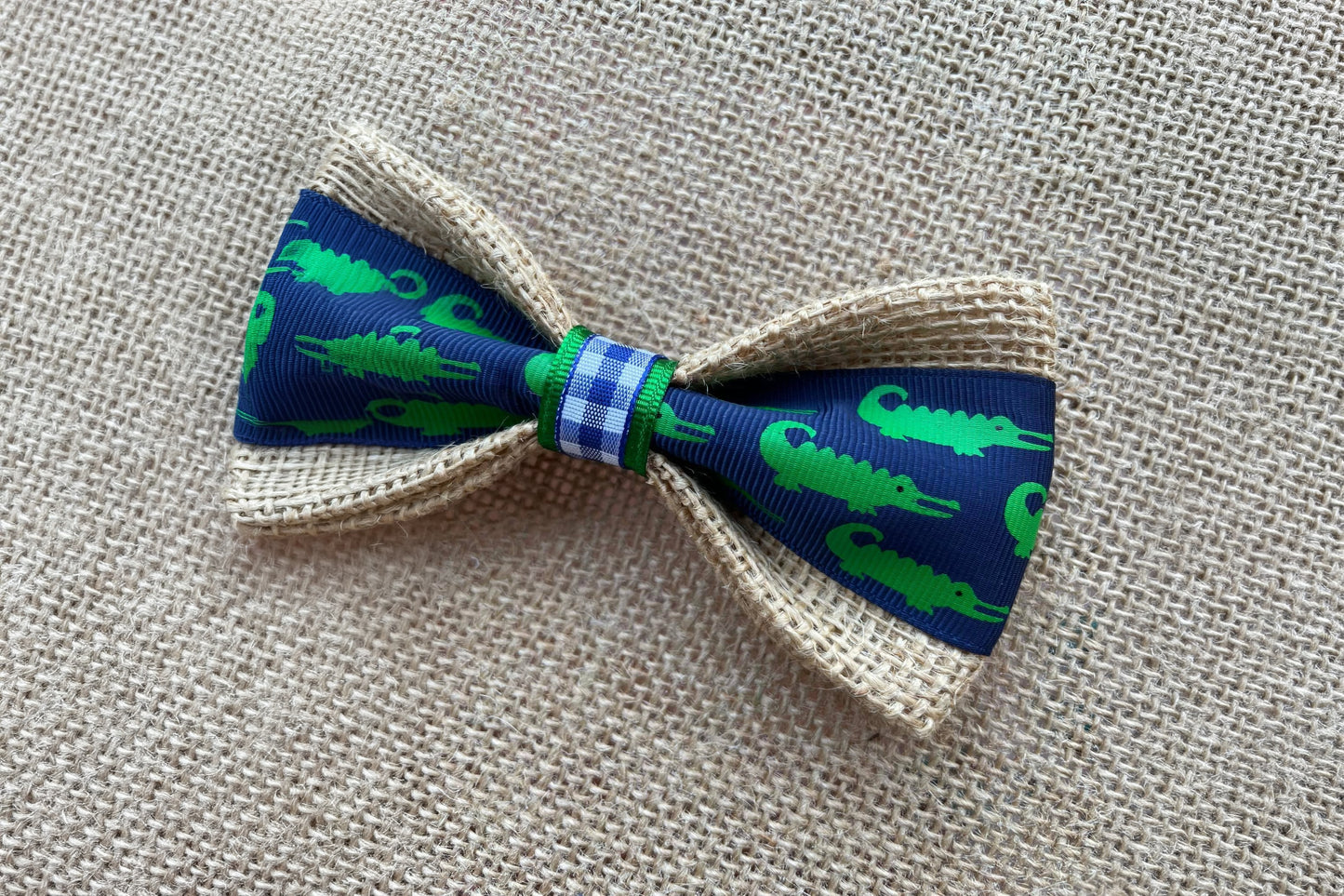 Pet bow tie with green alligator pattern on a blue background.