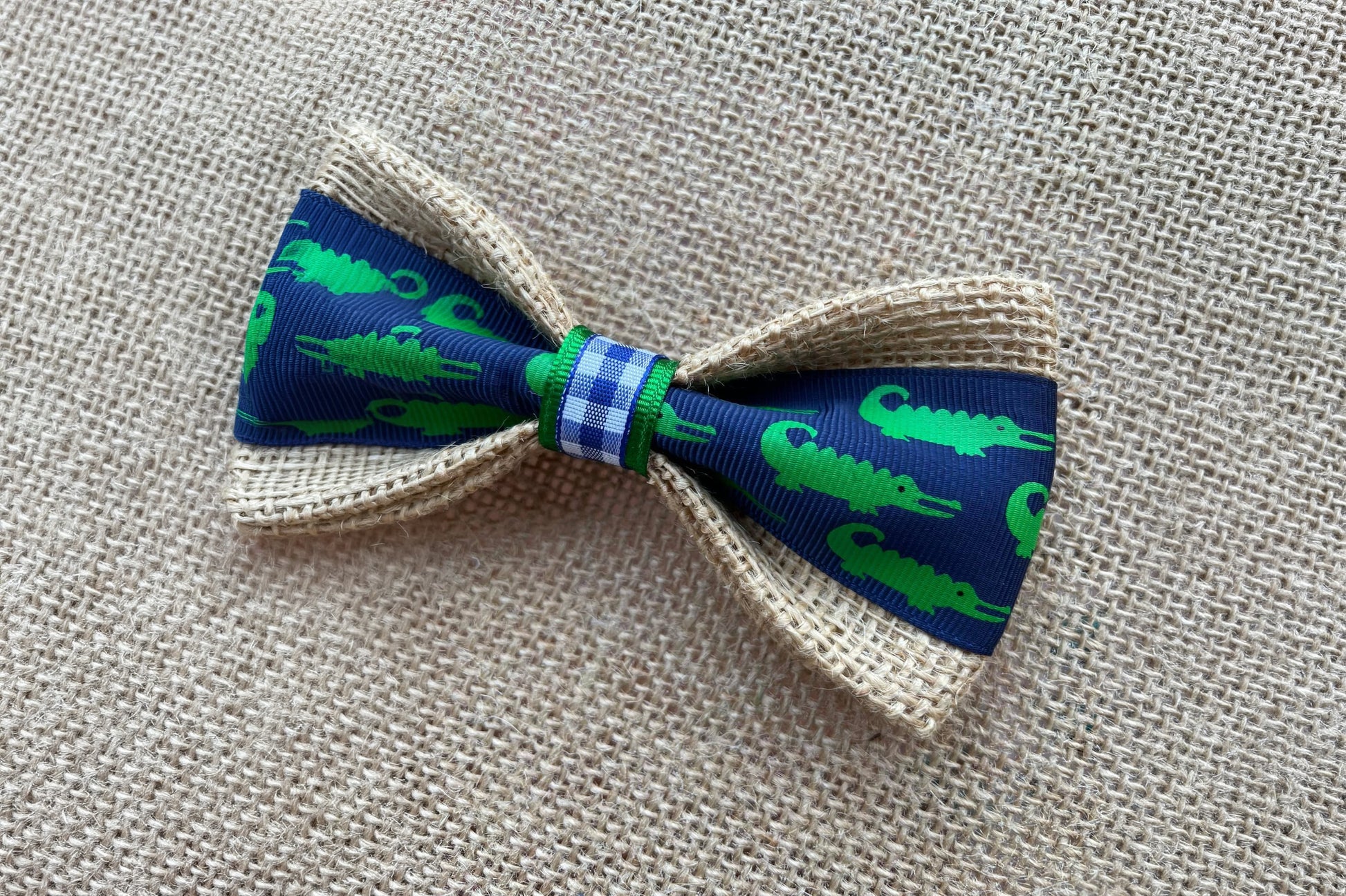Pet bow tie with green alligator pattern on a blue background.