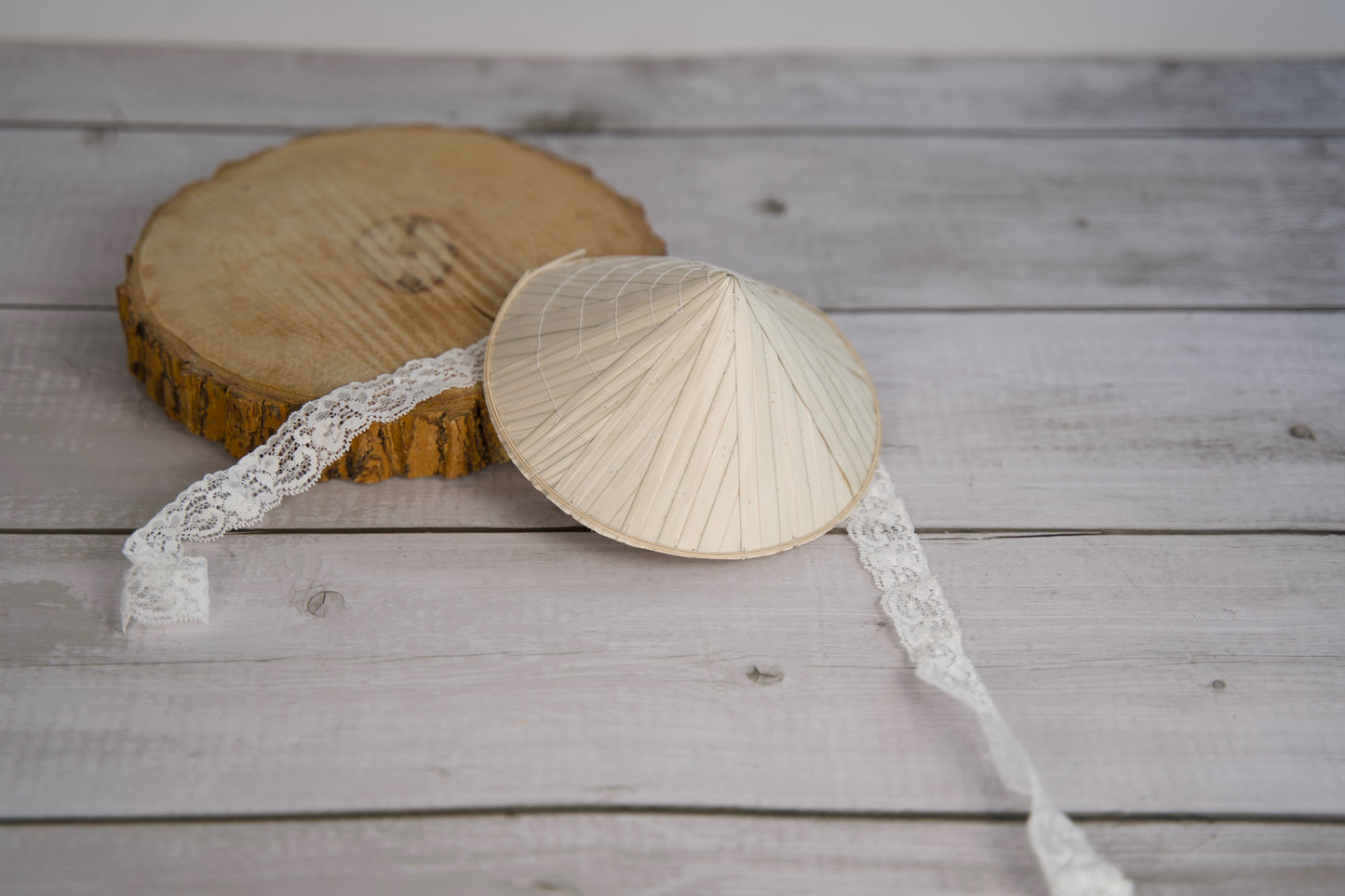 Chapeau conique traditionnel pour animaux, bordé de dentelle, posé sur une surface en bois.