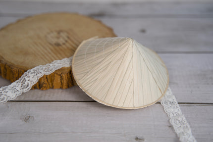 Chapeau conique traditionnel pour chien, posé sur une surface en bois et orné d'une bordure en dentelle.