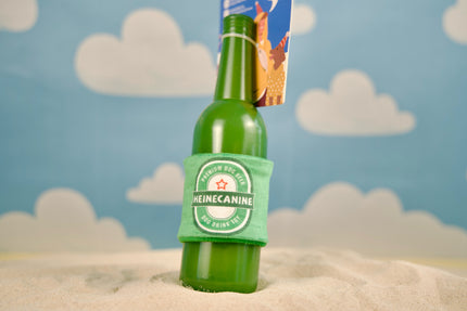 Rubber Heineken beer bottle imitation dog on sandbank.