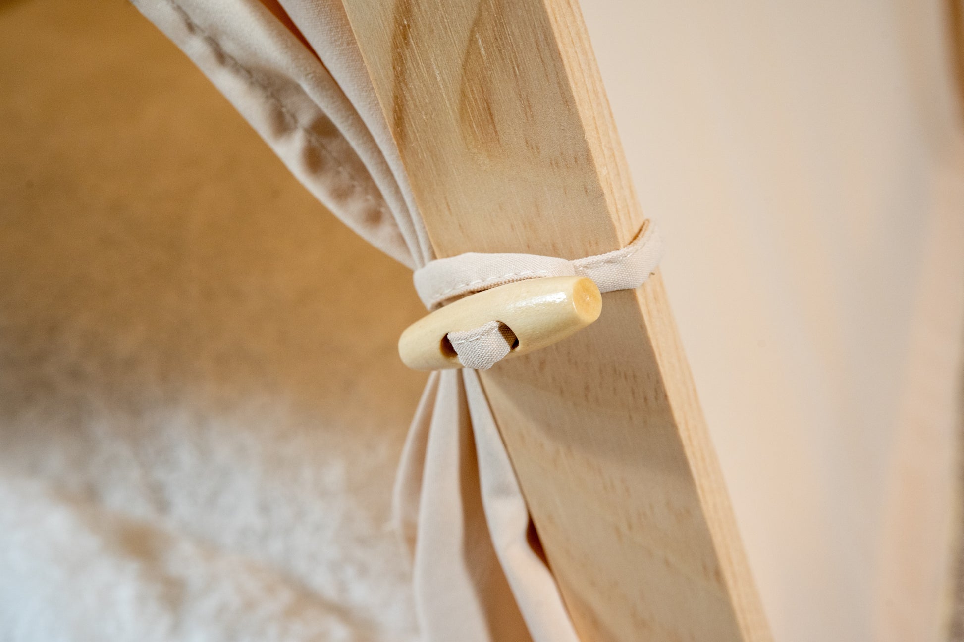 Close-up view of beige pet tent curtain clip. | Vue rapprochée de l'attache à rideaux de la tente beige pour animaux.