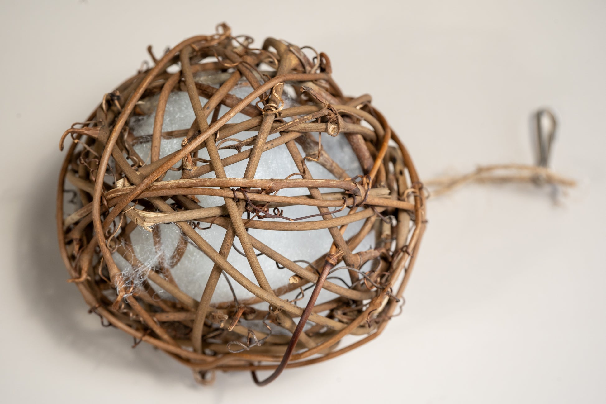 Close-up view of the rattan ball with integrated foam to entertain caged birds. | Vue rapprochée de la boule en rotin avec mousse intégrée pour divertir les oiseaux en cage.