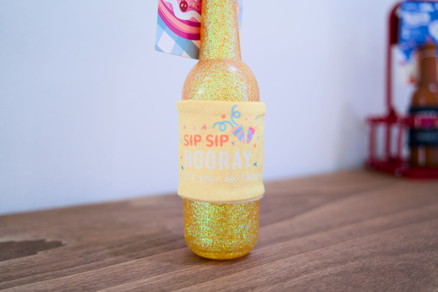 Happy birthday dog bottle with a colorful label on a wooden surface.
