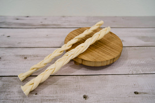 Two white braided collagen and beef cheek chews for dogs.|Deux friandises à mâcher tressées pour chien, au collagène et aux joues de bœuf, blanches.