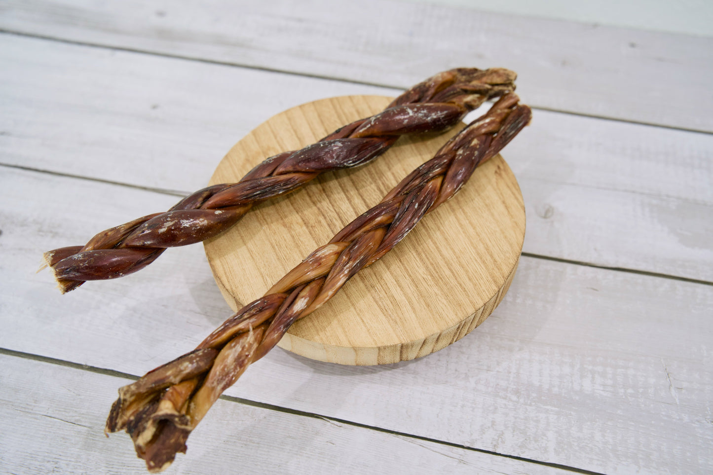 Two long braided dog treats with a dark reddish-brown color.