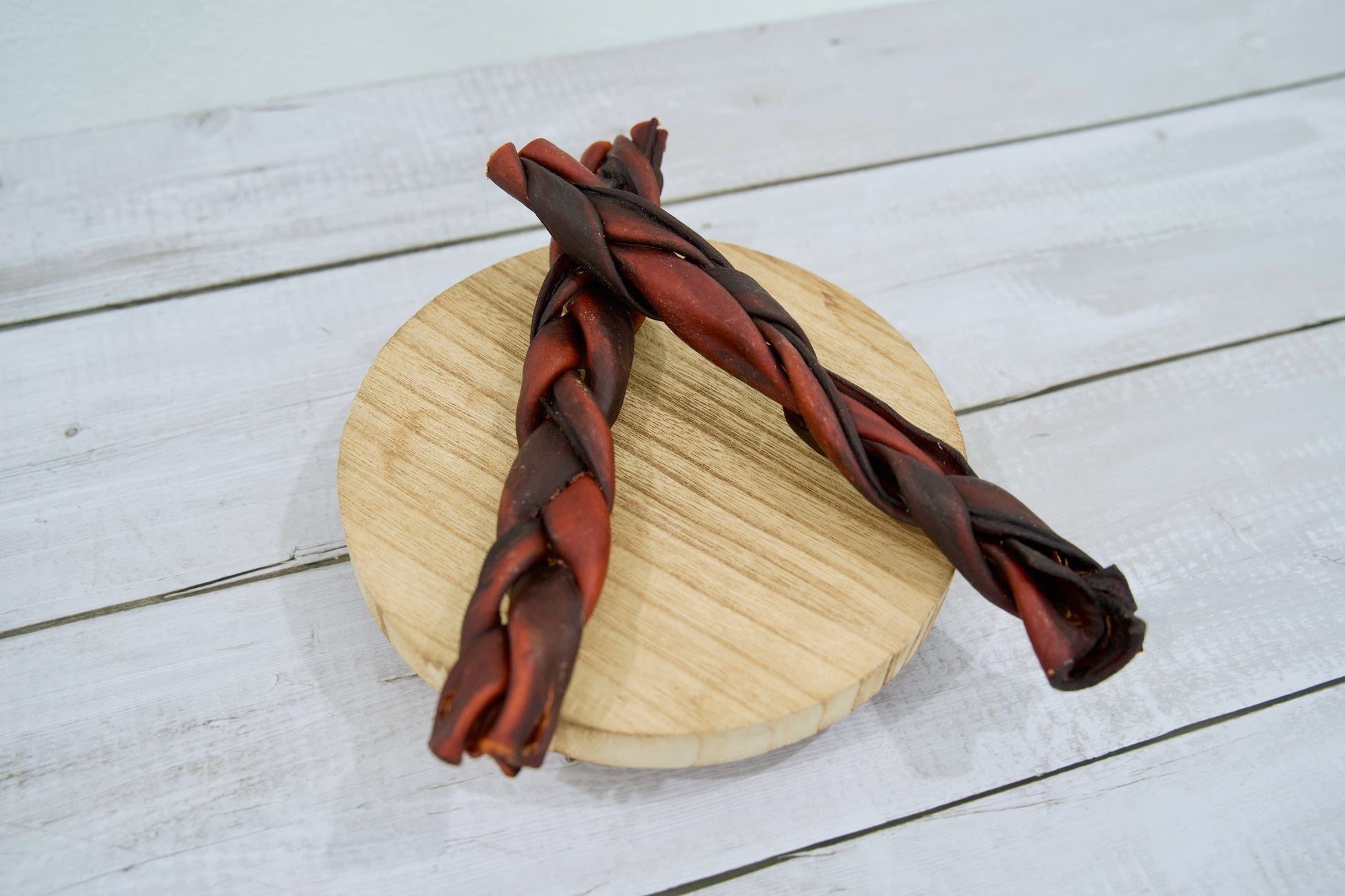 Two braided dog chew treats, one dark brown and one reddish-brown.