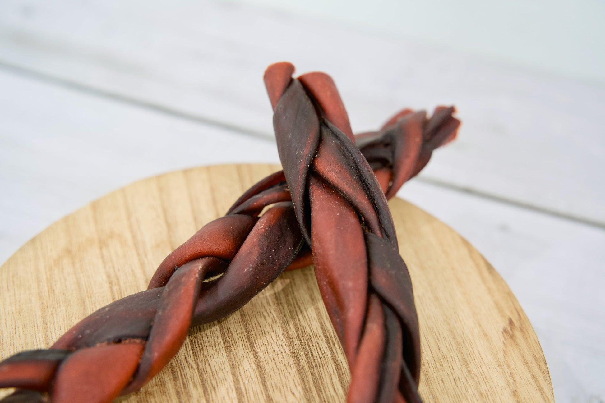 Close-up view of the two braided dog collagen chew treats, reddish-brown.