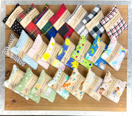 Collection de pochettes colorées en tissu pour chats, avec différents motifs, posées sur une surface en bois.