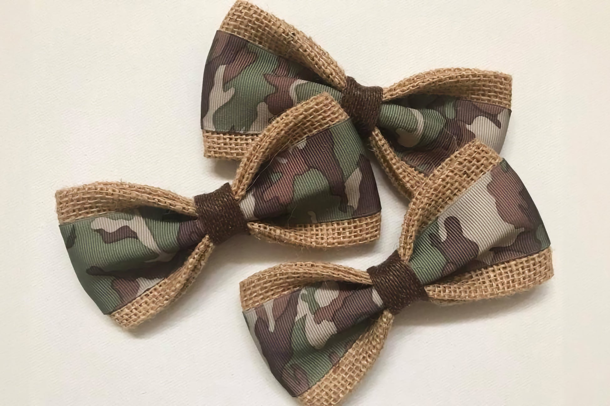 Three camouflage-patterned pet bow ties with brown accents on a white background.