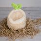 Small boat-shaped plush hideout with a green leaf on top, placed on a bed of brown seaweed.