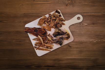 Viandes lyophilisées pour chiens sur une planche de charcuterie.
