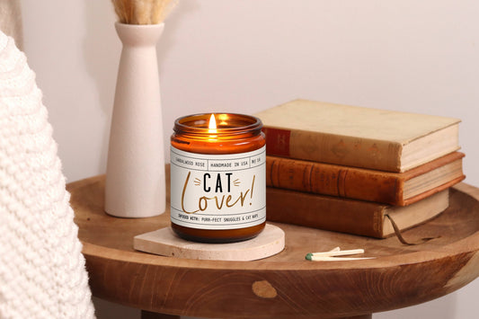 Cat-themed candle labeled Cat Lover on a wooden table, perfect gift for cat parents and cat lovers.|Bougie sur le thème des chats, portant l'inscription Cat Lover, posée sur une table en bois, le cadeau idéal pour les parents de chats et les amoureux des félins.