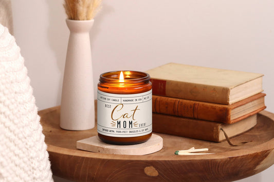 Pet-themed candle labeled Cat Mom on a wooden surface.|Bougie sur le thème des chat, portant l'inscription Cat Mom, posée sur une surface en bois.