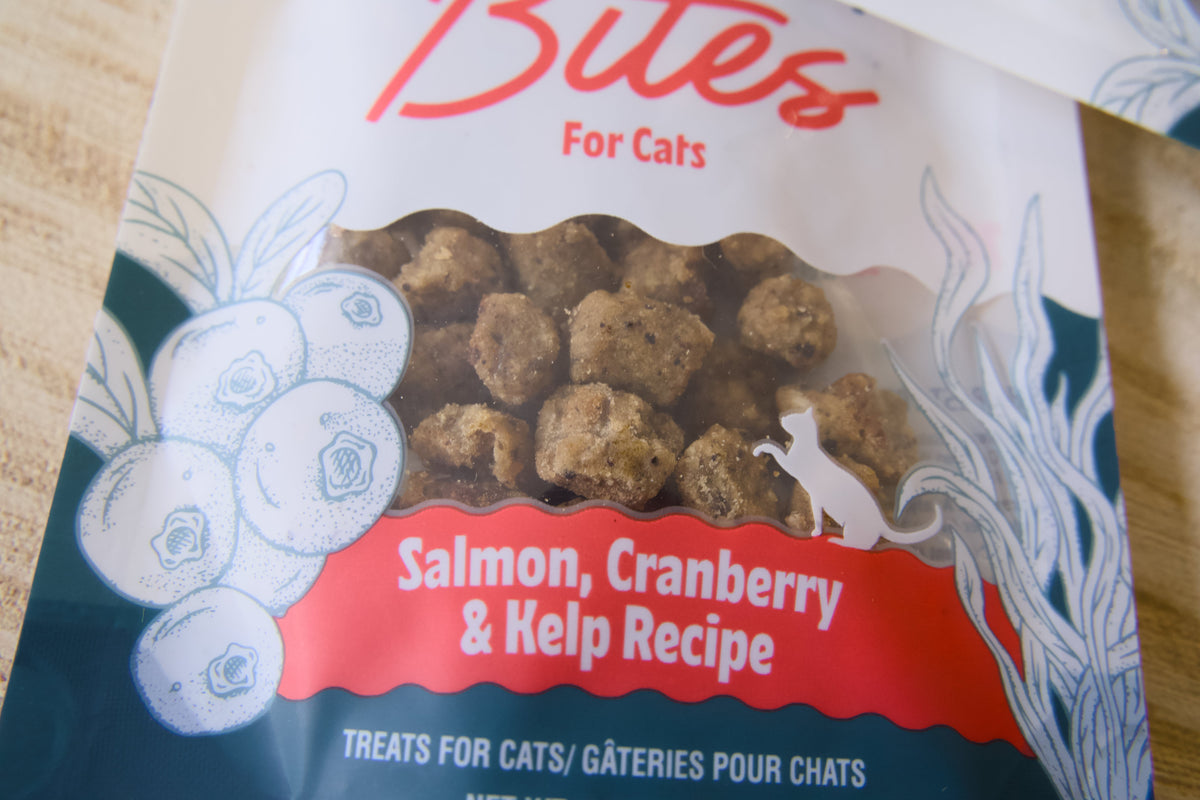 Gros plan sur un sachet de friandises pour chats à la recette saumon, canneberge et varech.