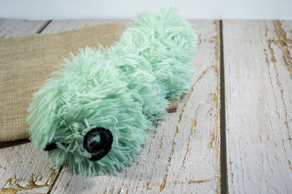 Side view of green cat plush toy in the shape of a caterpillar and filled with catnip.