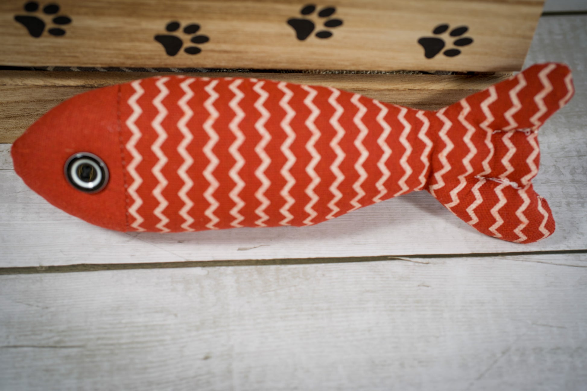 Close-up view of a cat toy with catnip in the shape of a red fish. | Vue rapprochée d'un jouet pour chat rempli à l'herbe à chat en forme de poisson rouge.