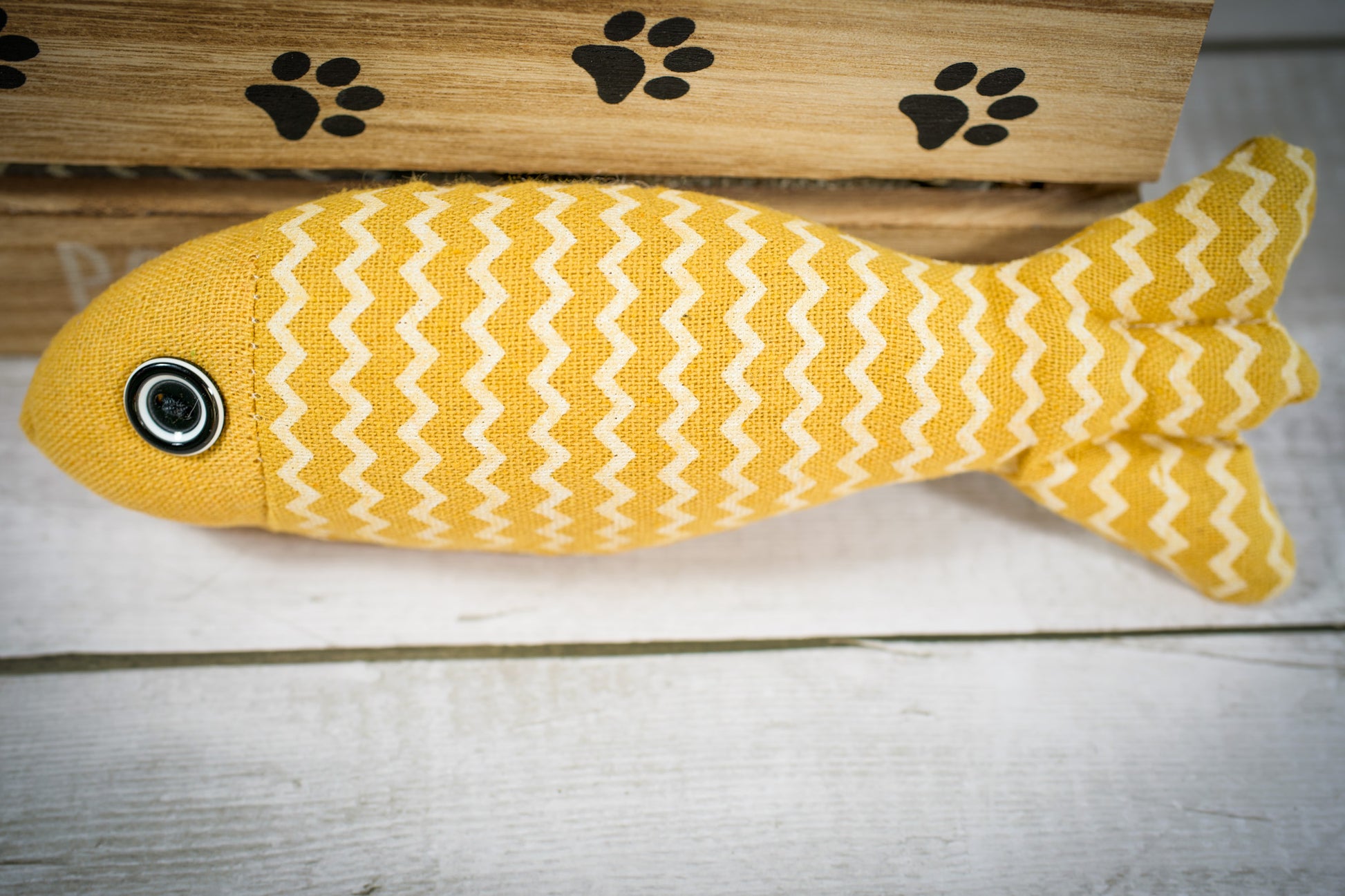 Close-up view of a cat toy with catnip in the shape of a yellow fish. | Vue rapprochée d'un jouet pour chat rempli à l'herbe à chat en forme de poisson jaune.