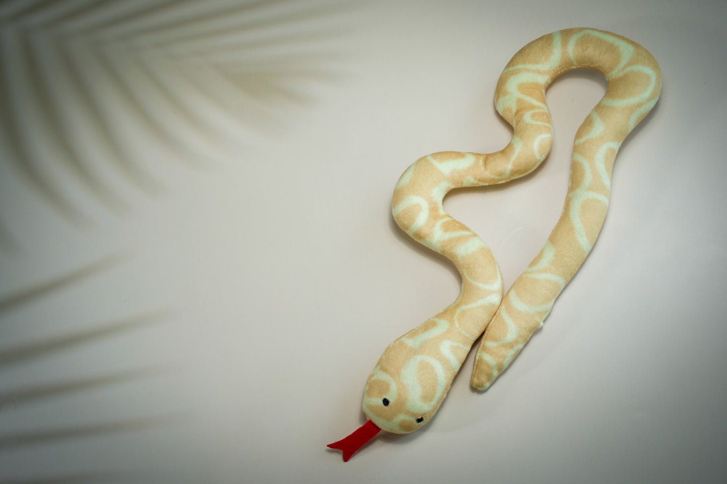Serpent en peluche rempli d'herbe à chat et de motifs circulaires jaunes et beiges.