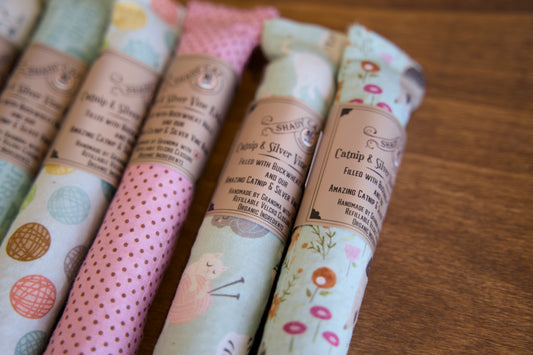 Set of cat kickers in various patterns on a wooden tray.|Ensemble de kickers pour chats aux motifs variés, présentés sur un plateau en bois.