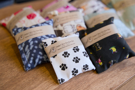 Quatre coussins remplis d'herbe à chat et de vigne argentée pour chats, avec différents motifs, posés sur une surface en bois.