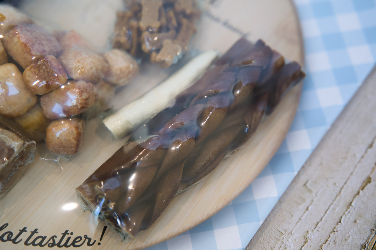 Close-up of a plate with dog chew treats items on a checkered tablecloth.