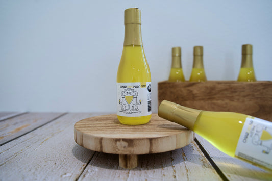 White wine bottles for dogs with wooden caps on a wooden surface and background.|Bouteilles de vin blanc pour chiens posées sur une surface et un arrière-plan en bois.