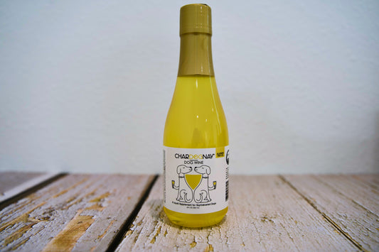 Bottle of Chardognay dog wine on a wooden surface with a white background.|Bouteille de vin pour chiens Chardognay sur une surface en bois, sur fond blanc.