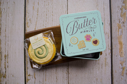 A chew cat toy filled with silvervine shaped like a matcha swirl cookie with a tin butter nibbles when buying 2 cookies.