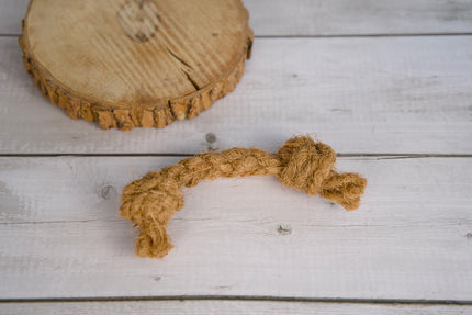 Jouet pour chien en corde nouée et coco, posé sur une surface en bois clair.
