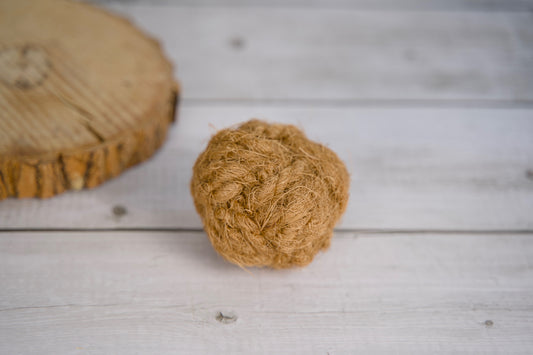 Dog ball made with coconut rope on a wooden surface.|Balle pour chien en corde de coco, posée sur une surface en bois.
