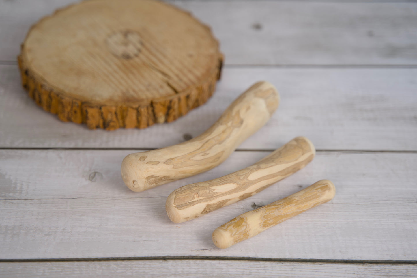 Trois jouets pour chien en bois de café, posés sur une surface en bois clair.