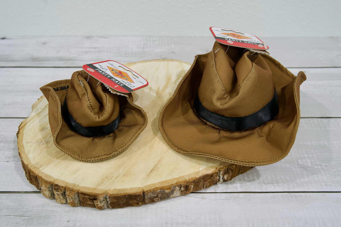 Deux chapeaux de cowboy pour chien avec des bandes noires, posés sur une surface en bois.
