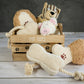 Wooden basket with neutral colored plush and rope toys for dogs.