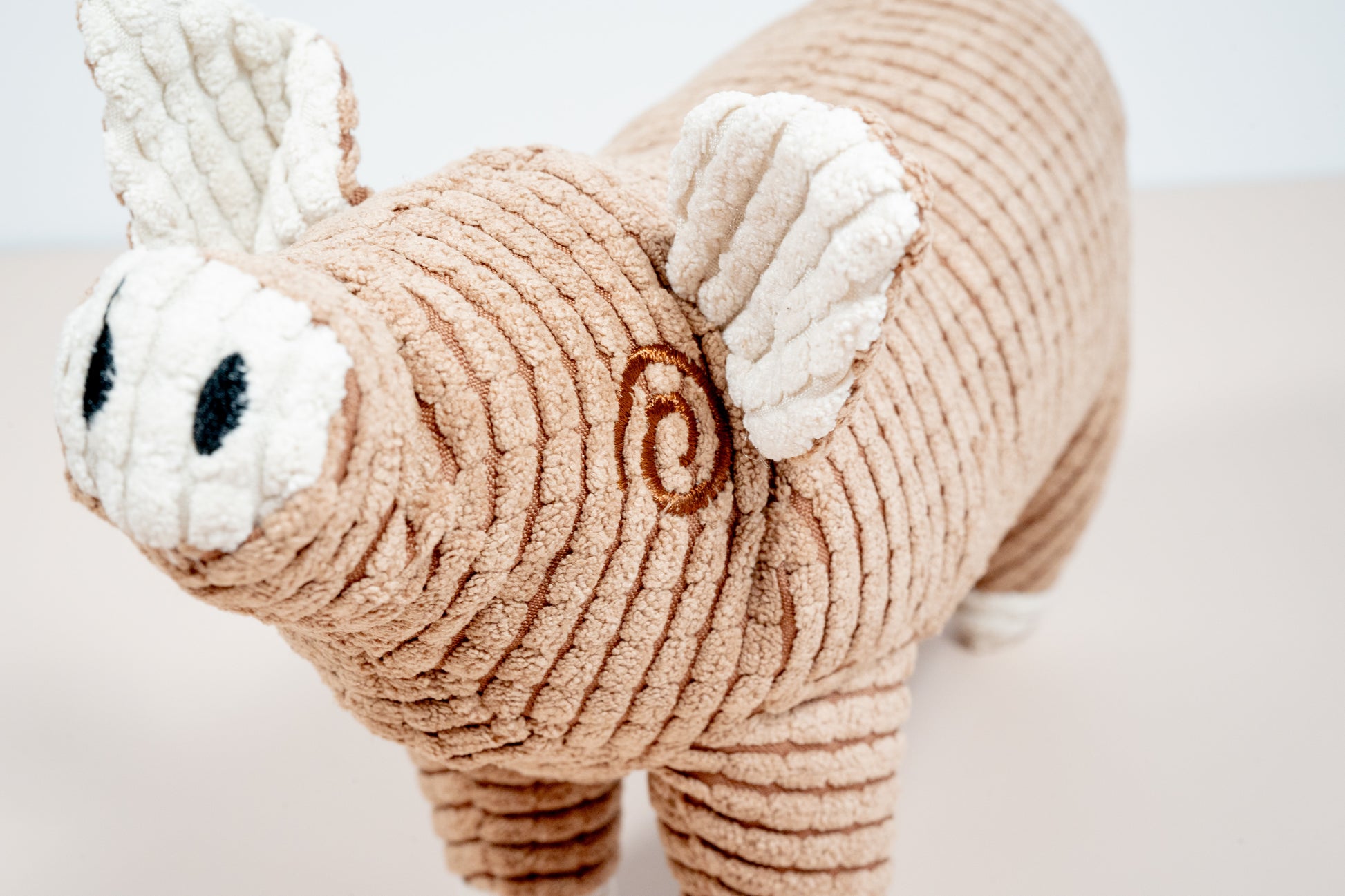 Close-up view of brown pig plush dog toy. | Vue rapprochée du jouet pour chien en peluche cochon marron.